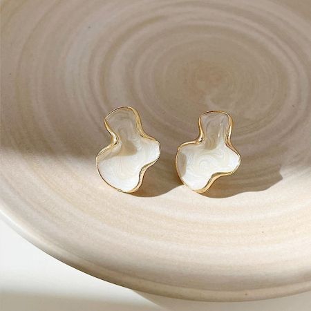 The set of 5 pairs of white enamel and gold earrings artfully arranged on a decorative plate.
