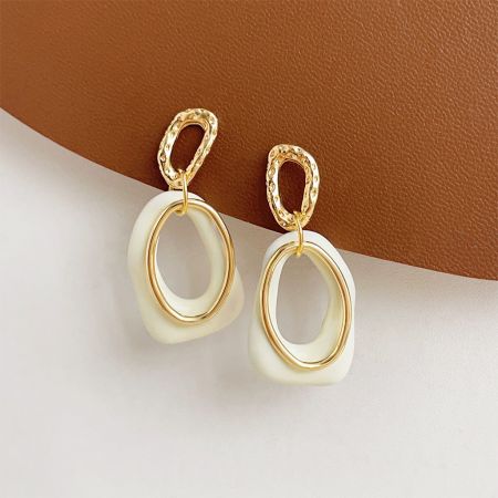 Boucles d'oreilles en émail blanc géométriques superposées en or 14K en gros (5 paires) - Une paire de boucles d'oreilles géométriques superposées en gros, avec une pièce ovale en émail blanc et une pièce supérieure texturée plaquée or 14K, sur un fond blanc propre.