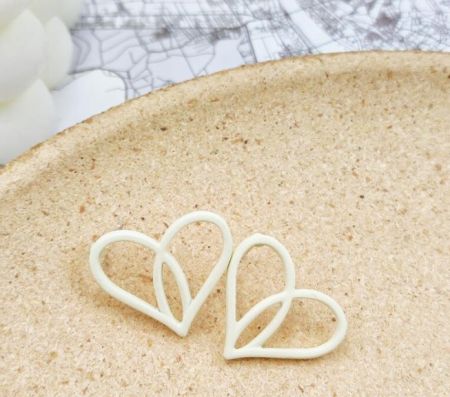 A pair of elegant white heart-shaped enamel earrings, perfect for a romantic summer look.