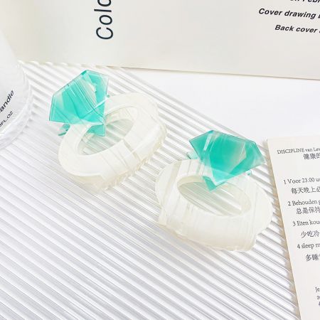 緑の宝石のアクセントが付いた白いアクリルヘアクリップのペアを一緒に表示。