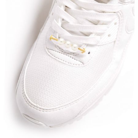 Etichetta per scarpe a tre perle elegantemente esposta sui lacci di una sneaker bianca.