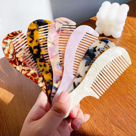 An assortment of six wide-tooth acetate combs in different colors and patterns.