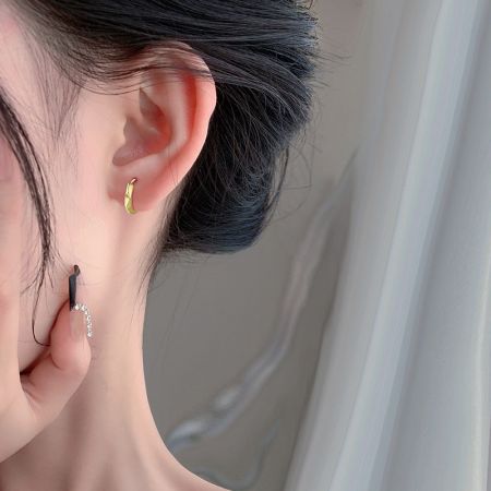 Modello che indossa gli orecchini huggie ottagonali in oro per mostrare scala e stile.