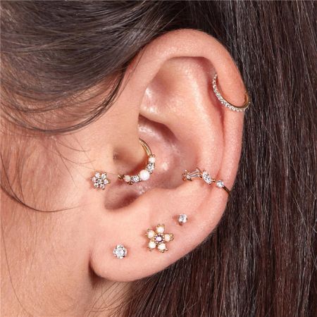 Model showcasing the tiny opal hoop earrings on the ear, paired with other studs for a stylish, layered look.