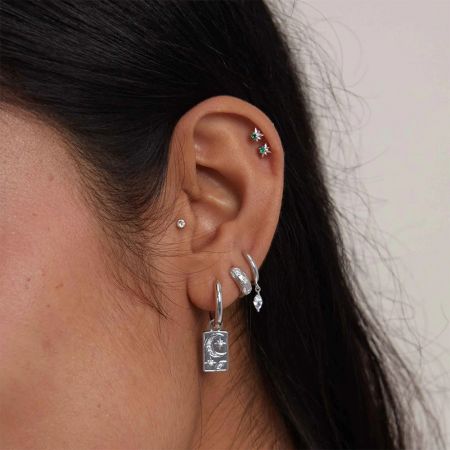 Un look per orecchie curato che presenta più orecchini in argento sterling, inclusi gli orecchini a goccia in CZ scintillante.