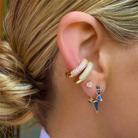 Orecchini a cuffia in argento sterling 925 con zirconia cubica senza piercing (set di 5) - L'orecchio di un modello adornato con un elegante set di orecchini a cuffia in argento sterling 925 e zirconia cubica, con un cuffia in oro e diamante e un orecchino a forma di fulmine blu.