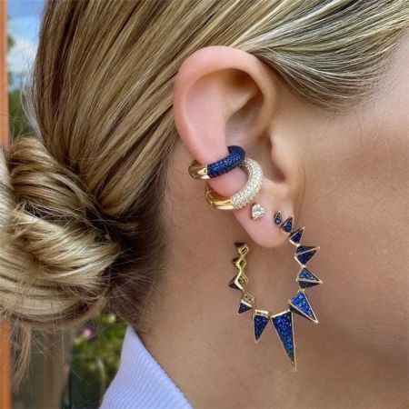 Modello che mostra un look stratificato con un orecchino a cuffia in argento sterling con accenti triangolari blu.
