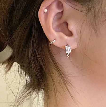 Close-up van het oor van een vrouw met de vintage vierkante zircon U-vormige oorbel, die de elegante pasvorm toont.