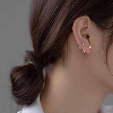 모델이 세 개의 스털링 실버 더블 볼 스터드 귀걸이로 큐레이션된 귀 모양을 선보이고 있습니다.