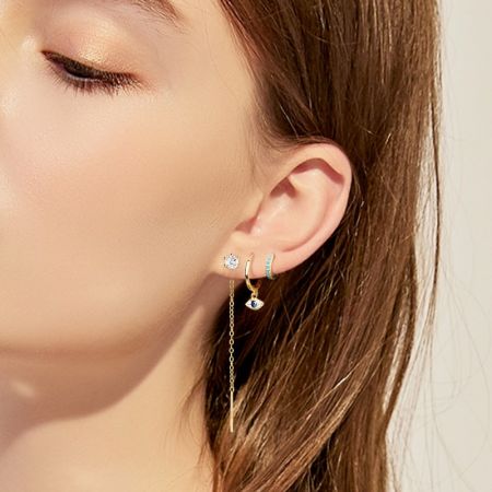 Model wearing a combination of earrings including the evil eye hoop for a stylish look.