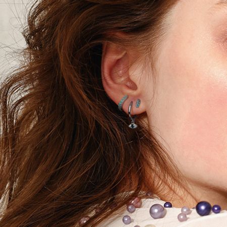 A lifestyle shot showing the evil eye earrings paired with a pearl necklace for an elegant ensemble.