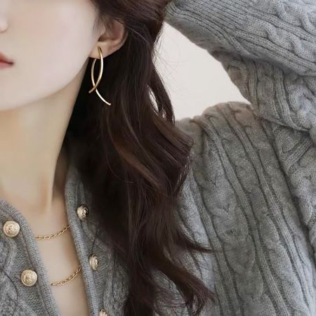 モデルが金メッキの魚型クリップイヤリングを着用し、そのエレガントな外観を披露しています。