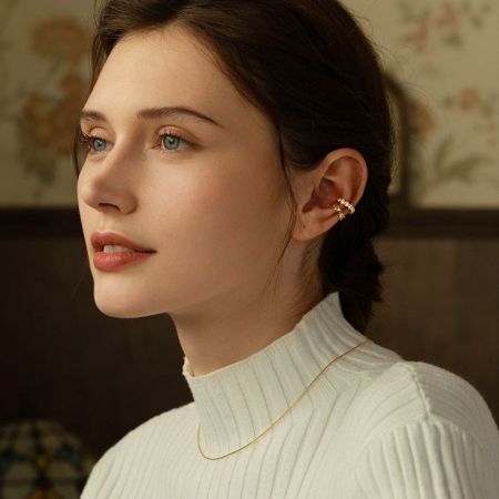 Een model draagt de mismatched gouden oorcuffs, die hun elegante aantrekkingskracht benadrukken.