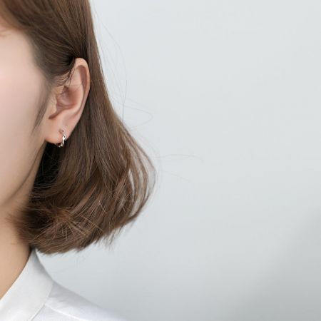 Un modello che mostra gli eleganti orecchini a cerchio intrecciati in argento sterling 925, evidenziando la loro dimensione e vestibilità.