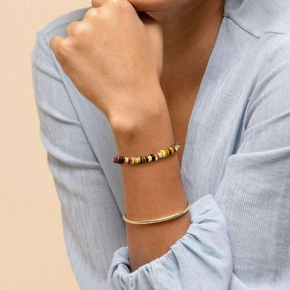 Muñeca del modelo adornada con el conjunto de pulseras bohemias de cuentas de piedra natural multicolor y doradas.