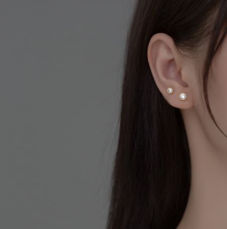 Un modello che mostra gli eleganti orecchini a bottone Halo in argento sterling 925, evidenziando il loro aspetto quando indossati.