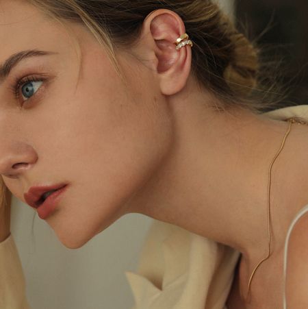 Model toont de veelzijdige styling van de gouden oorcuffs zonder piercings.