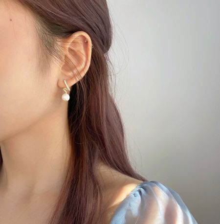 Modello che mostra l'elegante orecchino attorcigliato in argento sterling 925 con perla, evidenziando la sua dimensione e aspetto quando indossato.