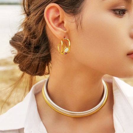 Una modelo mostrando los pendientes de piedra de ópalo, combinados con un collar de oro y plata.