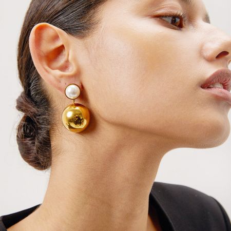 Perfil lateral de un modelo que muestra el elegante colgante de los pendientes de oro y perlas.