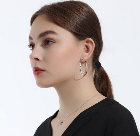 Modello che mostra gli orecchini a cerchio in argento sterling da 42 mm con texture a diamante per un senso di scala e stile.