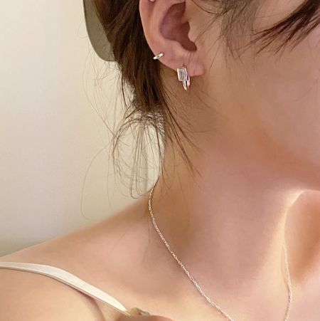 Een model dat elegant de zilveren zircon U-vormige oorbellen draagt, die haar stijl aanvult.