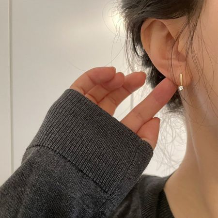Side profile of a woman wearing the minimalist 14K gold plated sterling silver hook earring.