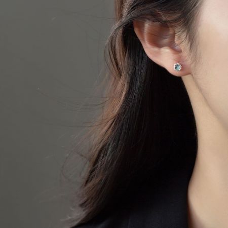 Modello che mostra la vestibilità elegante dell'orecchino a perno asimmetrico.