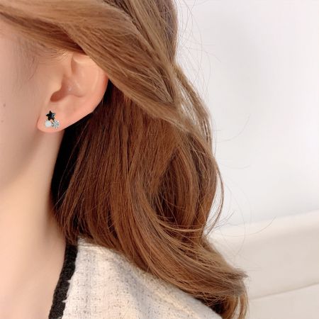 モデルがサイズとスタイルを示すために金メッキのブラックスタースタッドイヤリングを着用しています。