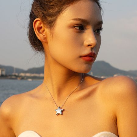 Portret van een vrouw die de elegante sterhanger slangenketting draagt.