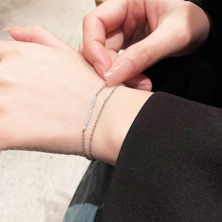 Un look chic y moderno con las pulseras de barra de zirconia de doble capa apiladas en la muñeca.