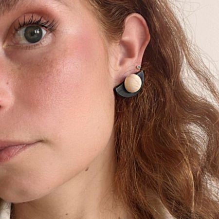 Lifestyle image showing a model wearing the unique black and wood fan-shaped earring.