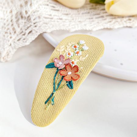 刺繍された花柄の黄色のヘアスナップクリップ。