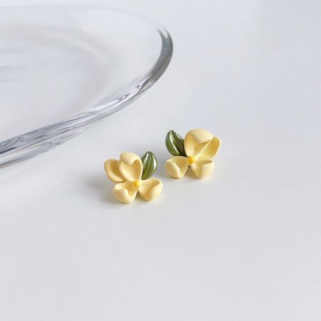 Boucles d'oreilles en fleur de gardénia 3D en émail jaune en gros (5 paires) - Une paire de boucles d'oreilles en fleur de gardénia 3D en émail jaune avec des détails de feuilles vertes, présentée sur un fond blanc.