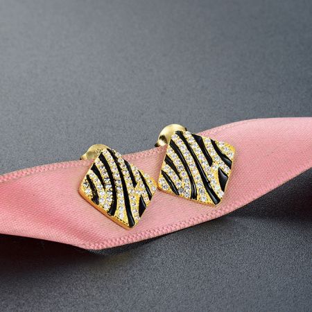 Primo piano degli orecchini a perno a forma di zebra placcati in oro che mostrano il motivo intricato e i dettagli delle pietre.