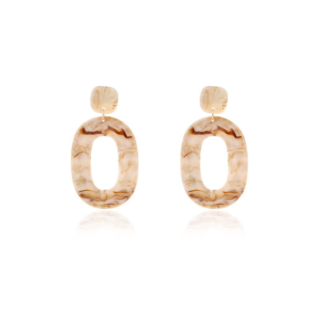 Une paire de boucles d'oreilles pendantes ovales larges en résine présentant un magnifique motif marbré dans des tons beige, crème et marron.
