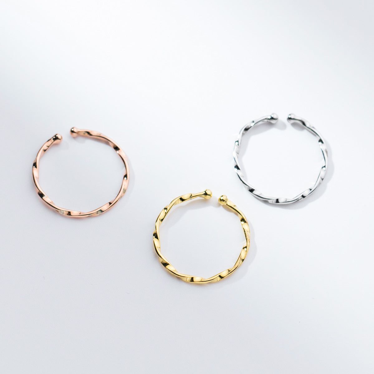 Un conjunto de tres anillos apilables en estilo trenzado de plata esterlina 925 ajustables en acabados de plata, oro y oro rosa.
