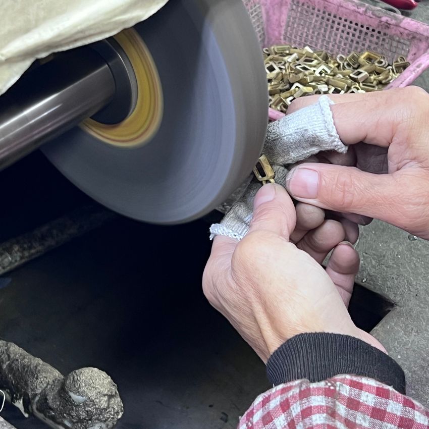 Ein geschickter Handwerker bei JR Fashion Accessories führt sorgfältig den Präzisionsschliffprozess an einem maßgeschneiderten Schmuckstück durch und sorgt für eine glatte und makellose Oberfläche.
