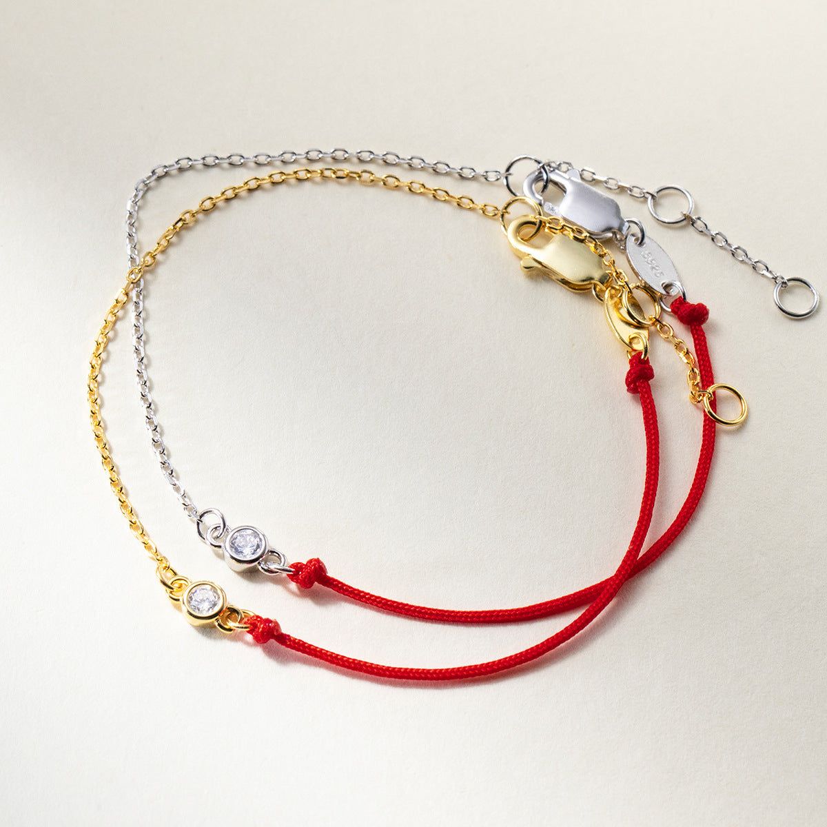 Un conjunto al por mayor de cinco pulseras minimalistas que presentan plata esterlina 925, cadenas de oro y cordones rojos con encantos de circonita cúbica.