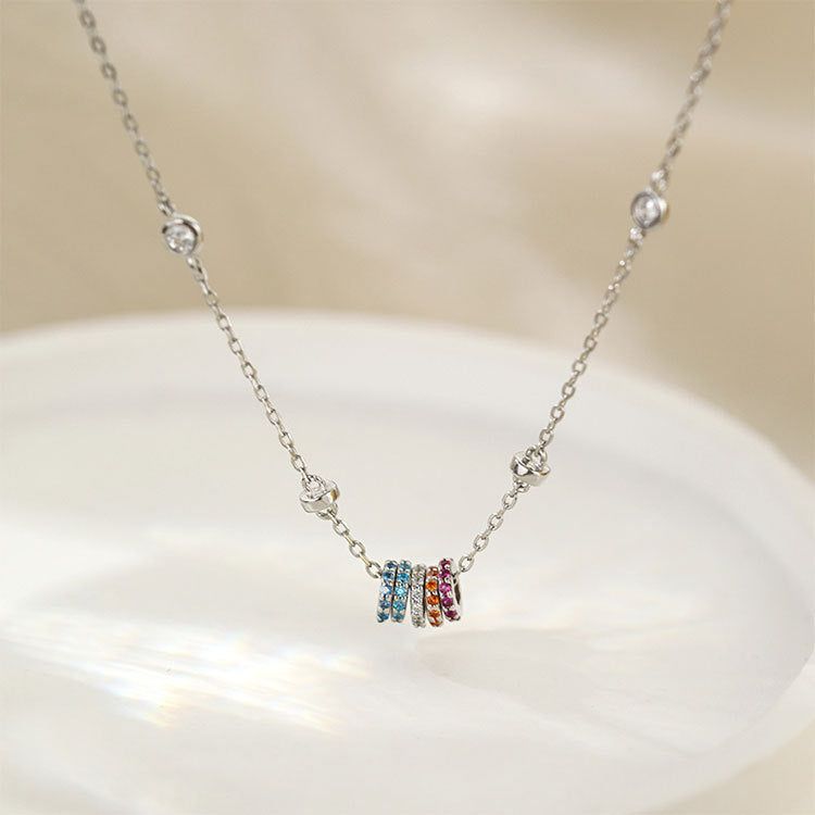 A close-up of the 925 sterling silver necklace with a pendant of five rainbow zircon circle charms on a white background.