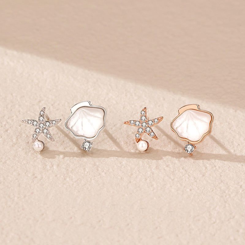 Un set di orecchini a perno a tema oceanico in argento sterling 925, che mostrano design di stelle marine e conchiglie in finiture sia in argento che in oro rosa su uno sfondo bianco.