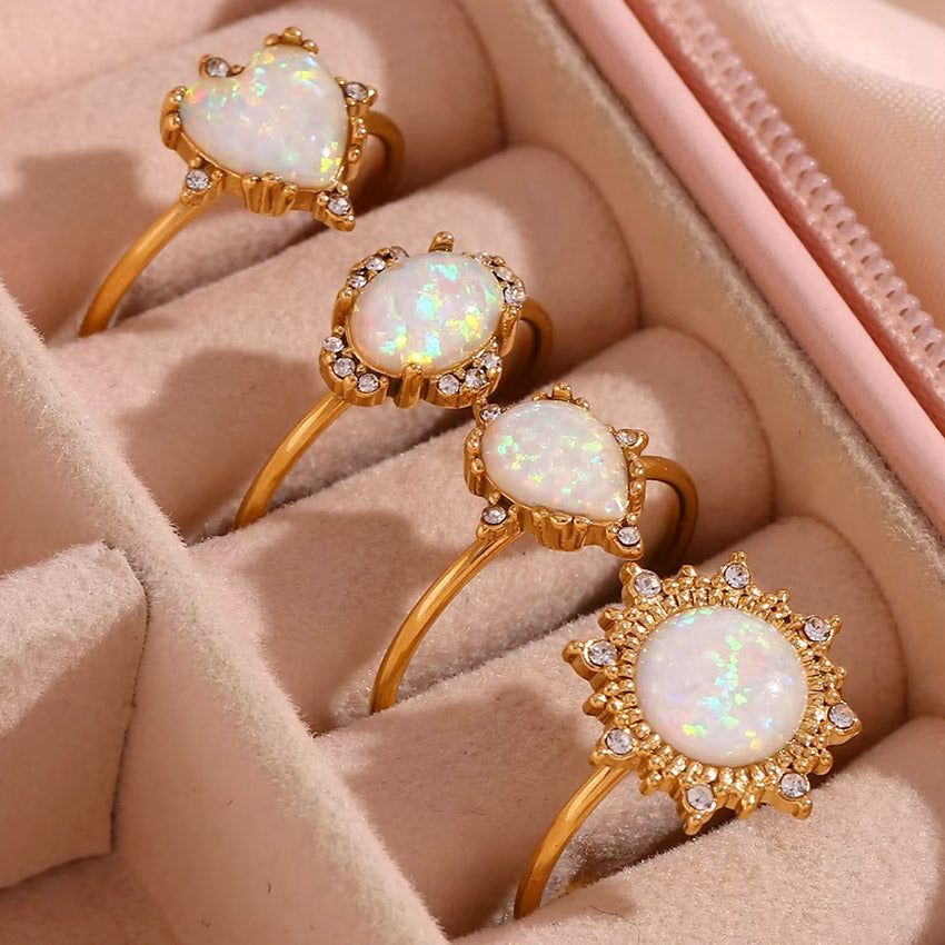 A set of four elegant, adjustable stainless steel opal rings with 18K gold plating and zircon accents, beautifully displayed in a pink velvet jewelry box.