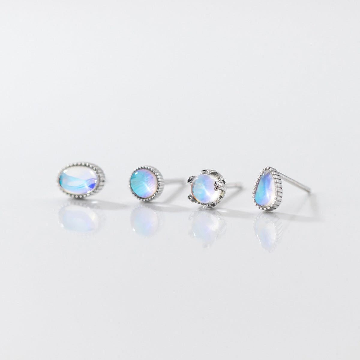 Una collezione di quattro paia di orecchini a perno in argento sterling 925 con pietre di luna iridescenti, che mostrano vari design eleganti.
