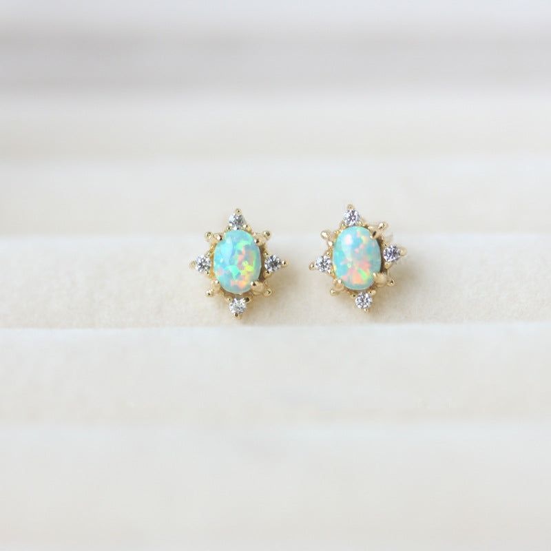 A pair of 925 sterling silver gold-plated oval stud earrings with four-prong opal stones and diamond accents, shown on a clean white background.