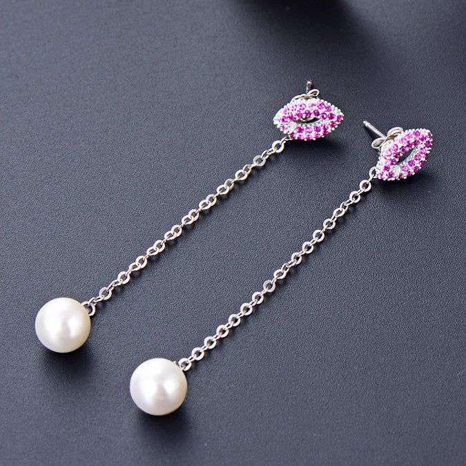 Un paio di orecchini lunghi con nappina in argento sterling 925 con una goccia di perla bianca e un chiodo decorato con pietre rosa e bianche.