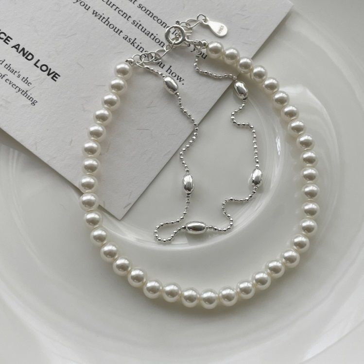 Ein wunderschönes 925 Sterlingsilber-Perlen-Doppelkettenarmband, das sein zartes Design und die glänzenden Perlen vor einem klaren Hintergrund präsentiert.