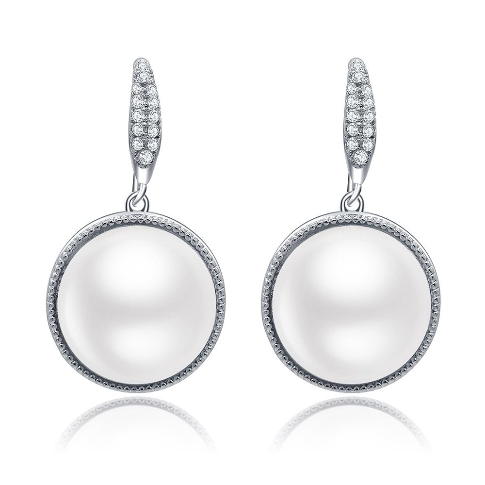 Un gros plan des boucles d'oreilles pendantes en perles imitations, mettant en avant la perle brillante sur un côté et les pierres en zircon cubique environnantes serties en laiton plaqué rhodium.