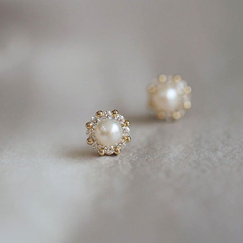 A pair of elegant 925 sterling silver stud earrings featuring a central pearl surrounded by a halo of sparkling zircon stones, showcasing a classic French design.