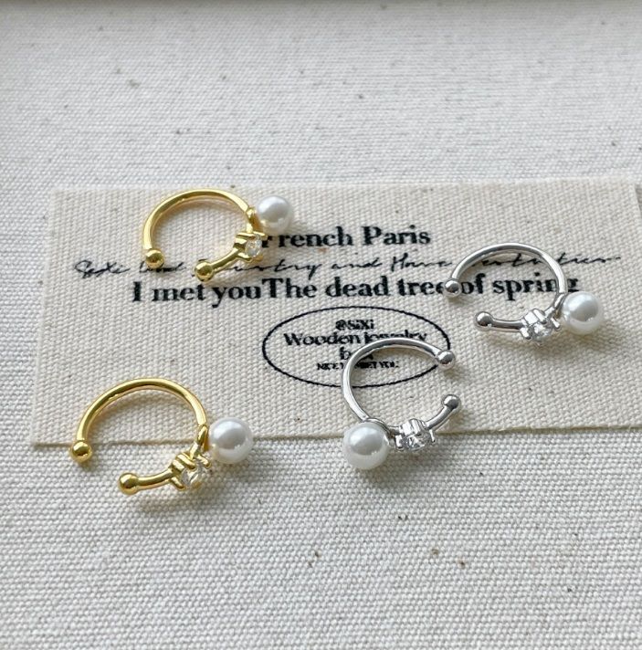 Un primo piano del bracciale auricolare a clip in argento sterling 925 con perla, che mostra i dettagli della perla lucente e delle gemme scintillanti, disponibile nelle finiture oro e argento.