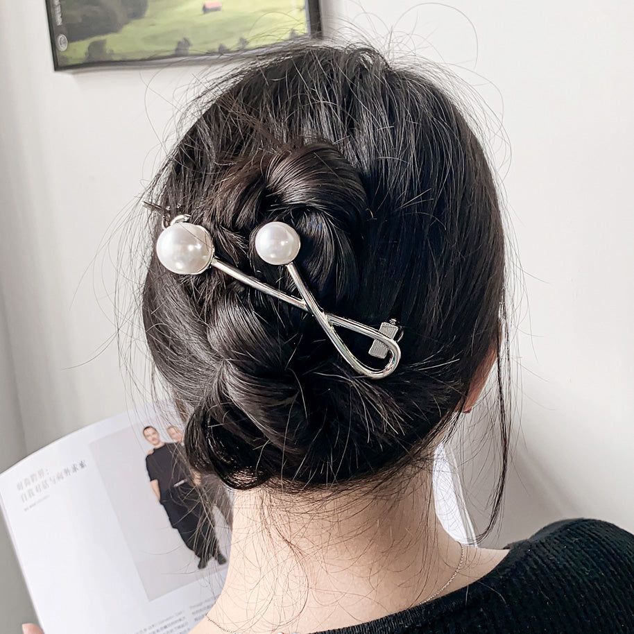 A stylish metal alloy twisted hair clip adorned with two elegant white pearls, perfect for daily wear.